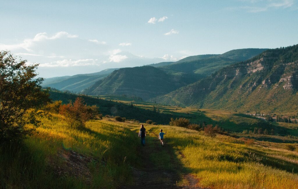 expansive field with mountains and family walking on trail